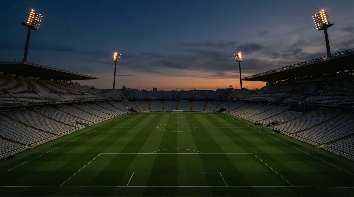 An empty football stadium with floodlight masts at dusk