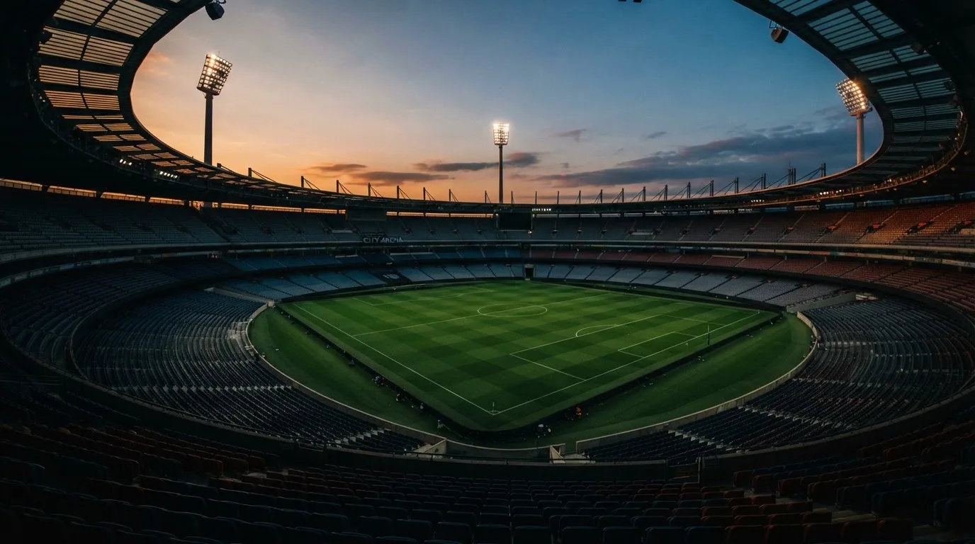 An empty football stadium with floodlight masts at dusk
