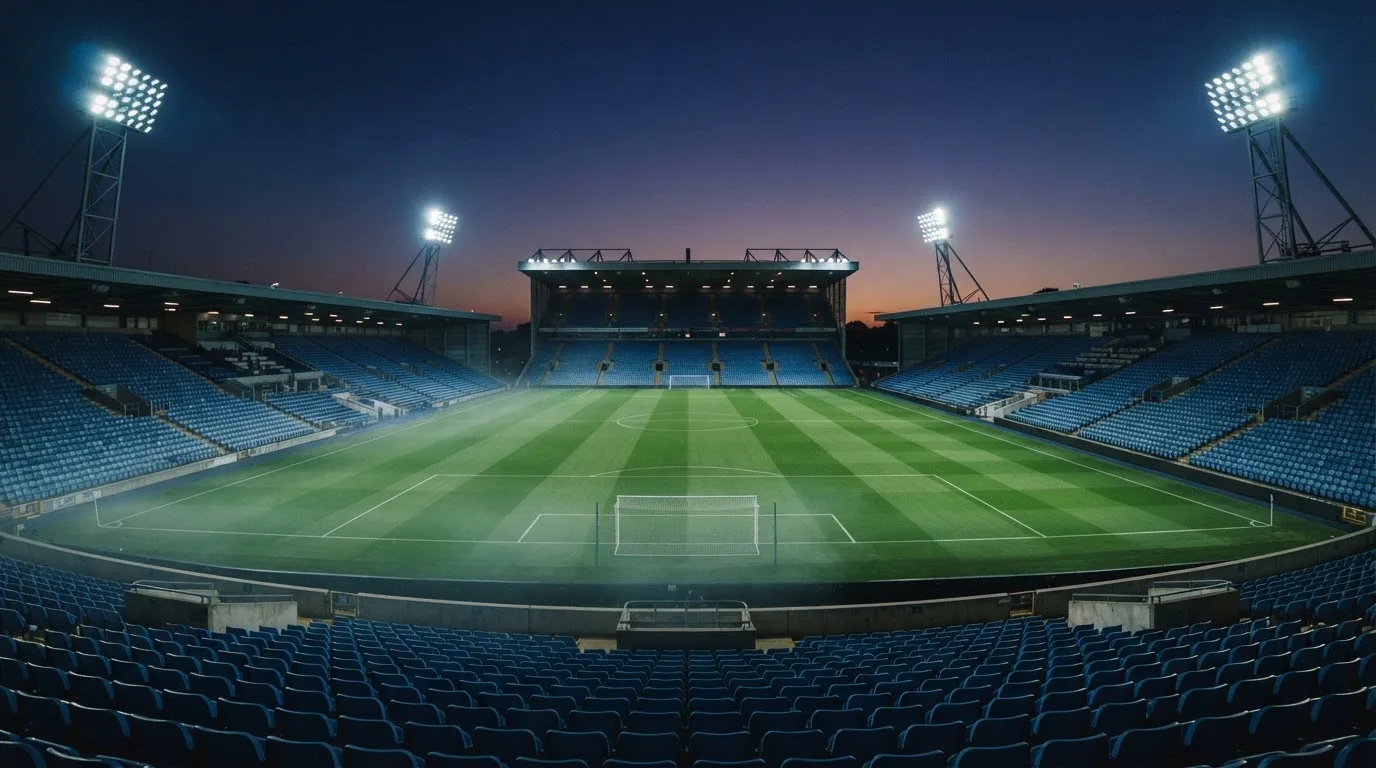 An empty football stadium with floodlight masts at dusk