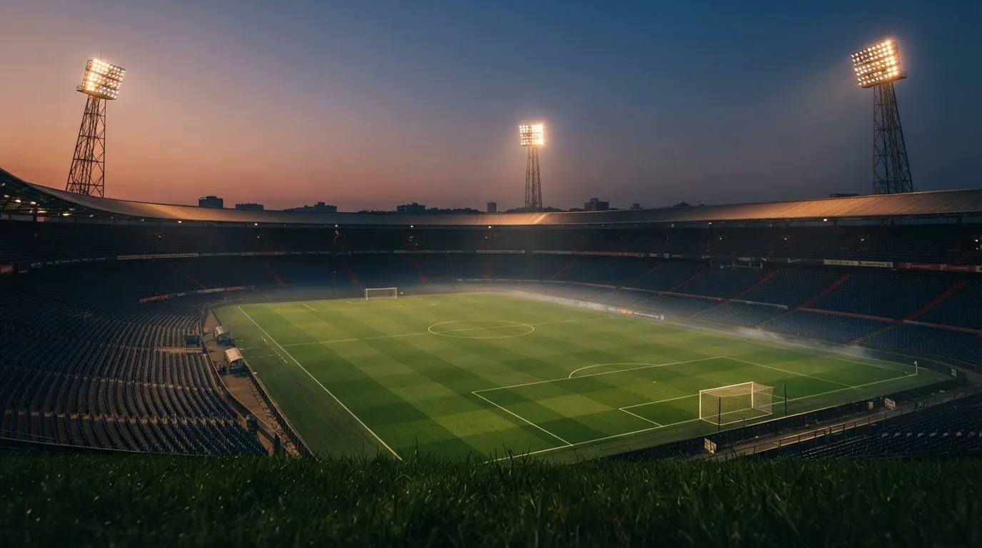 An empty football stadium with floodlight masts at dusk
