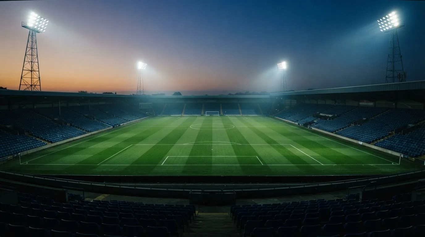 An empty football stadium with floodlight masts at dusk