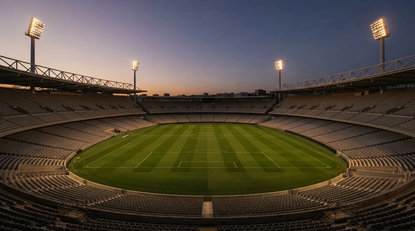 An empty football stadium with floodlight masts at dusk