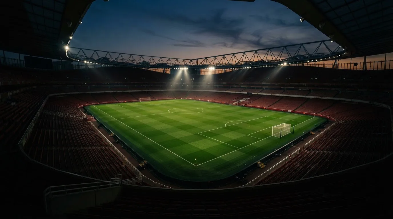 An empty football stadium with floodlight masts at dusk
