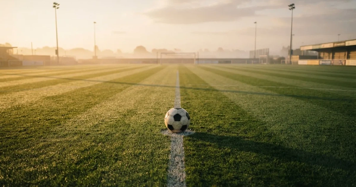 A ball on the centre spot of a grass pitch in morning light
