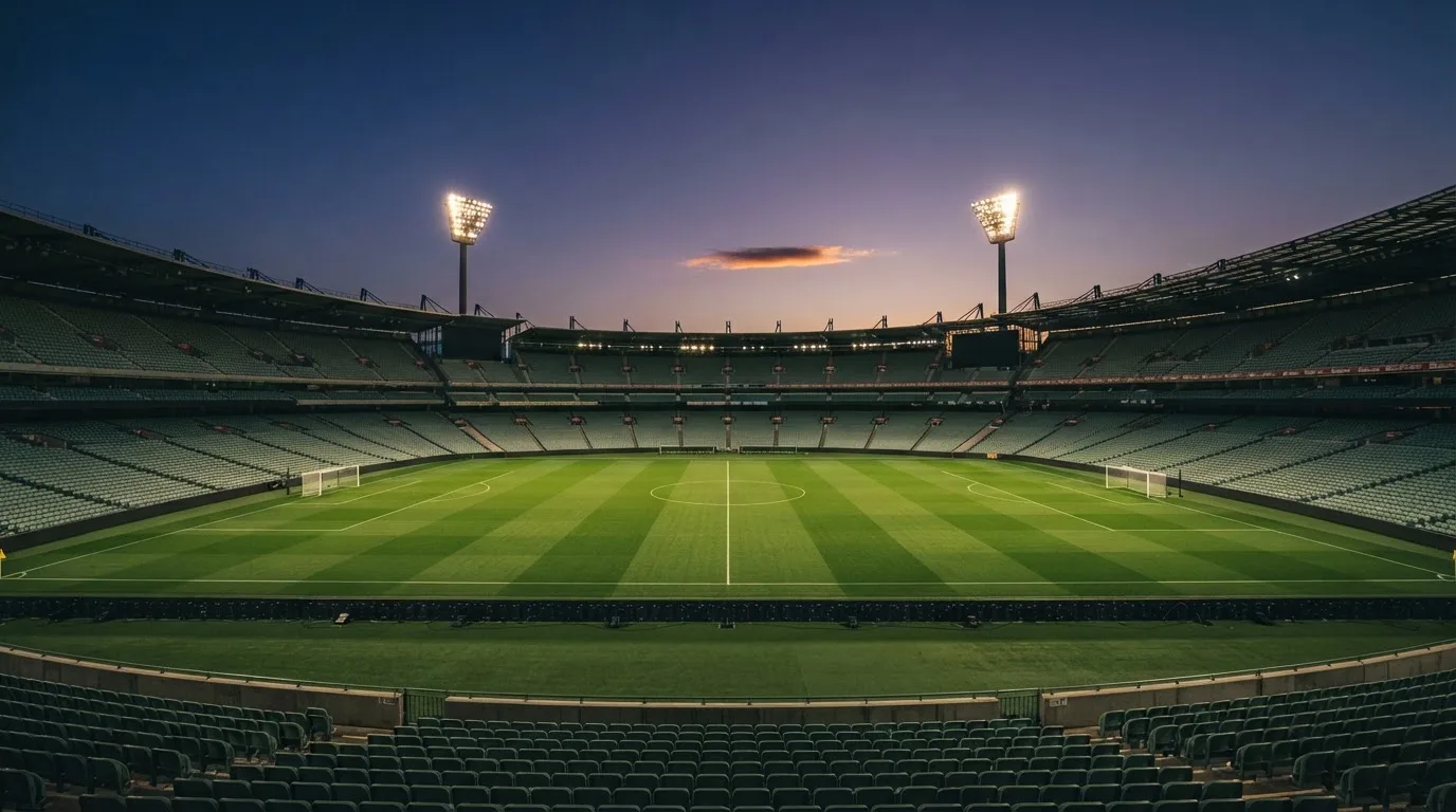 An empty football stadium with floodlight masts at dusk