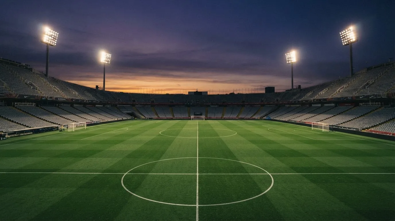 An empty football stadium with floodlight masts at dusk
