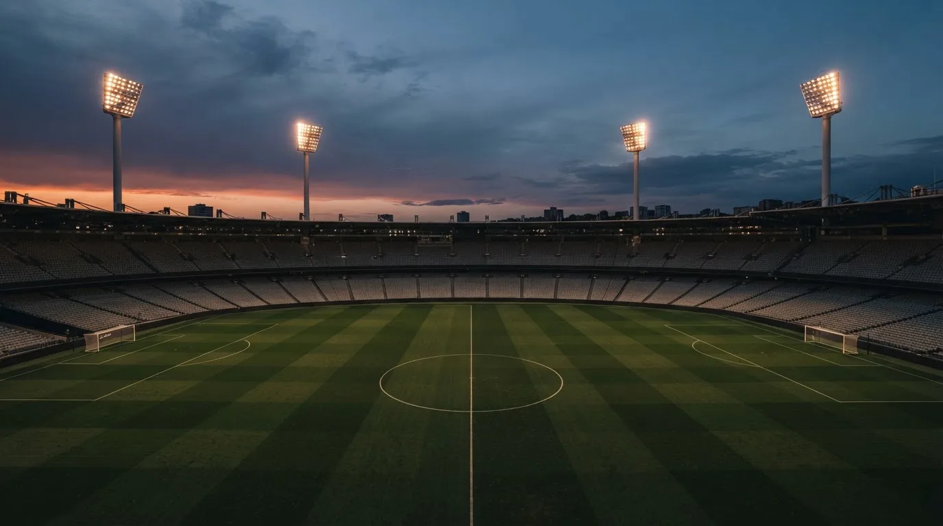 An empty football stadium with floodlight masts at dusk