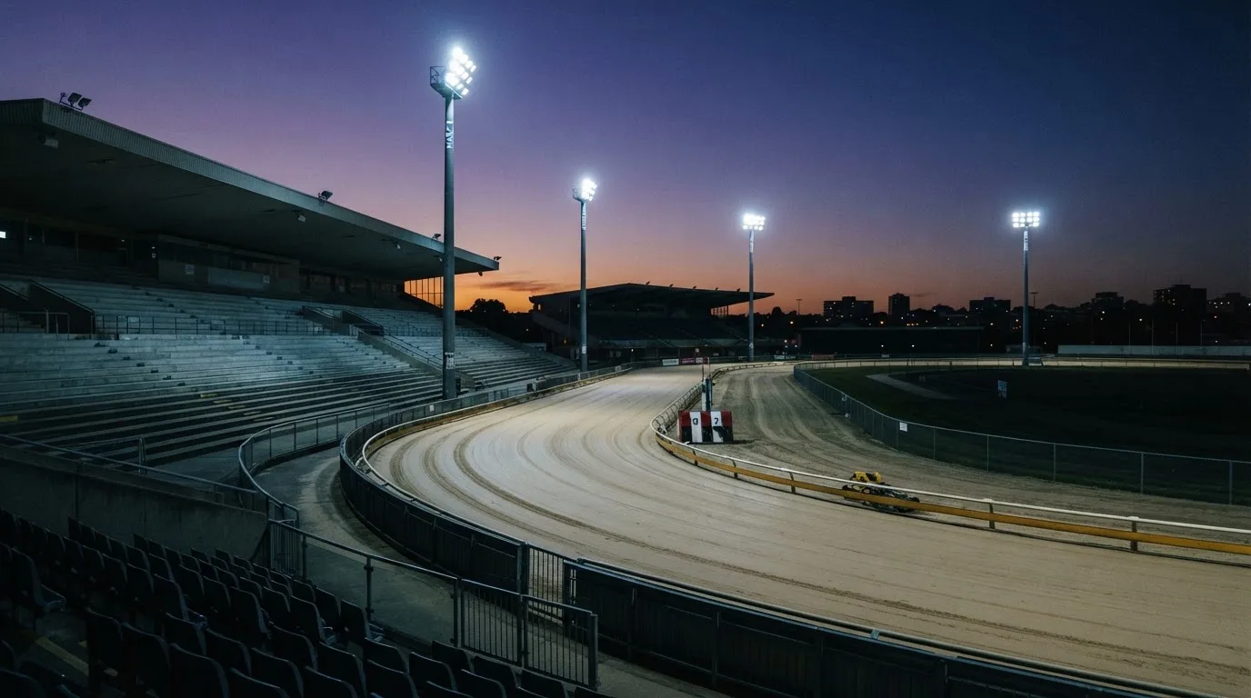 An empty football stadium with floodlight masts at dusk