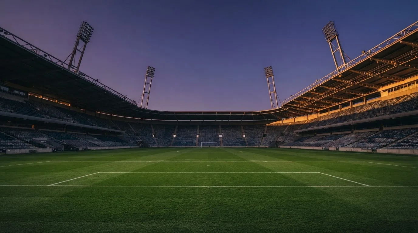 An empty football stadium with floodlight masts at dusk