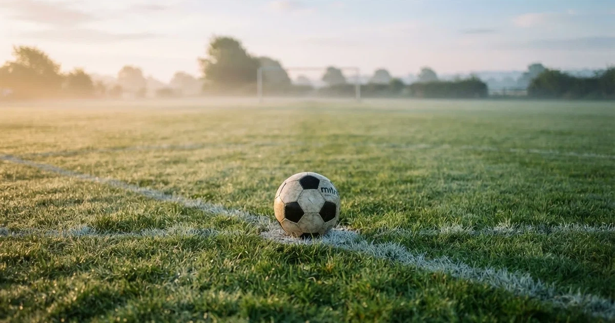 A ball on the centre spot of a grass pitch in morning light